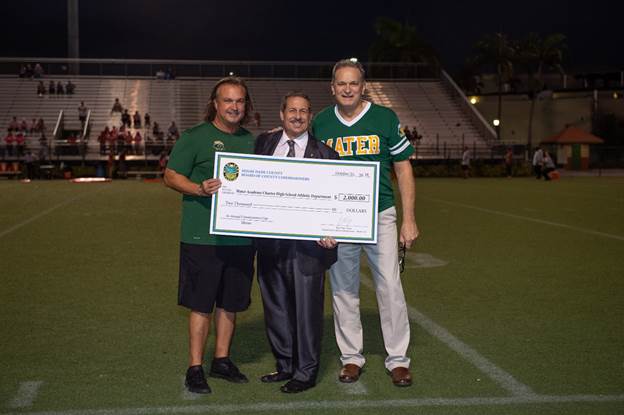 Miami-Dade County Commissioner Jose “Pepe” Diaz (center) presents Mater Academy Lions Athletic Director Luis Sanchez (left) and VicePrincipal Jose Nunez a $2,000 check for their athletic department after the team’s Commissioners Cup victory.