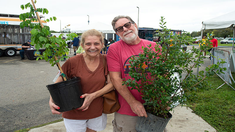 A man and woman holding small potted trees