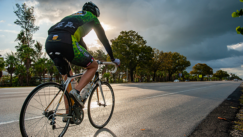 bicyclist riding bicycle on the side of the road