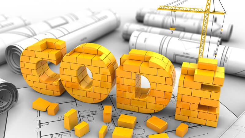 Building plans and blocks that spell out the word CODE.