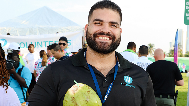 Michael Bello at an outdoor event holding a coconut