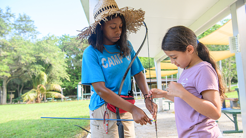 A counselor and camper doing archery.