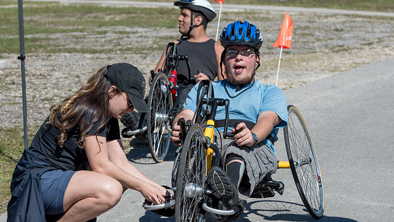 Man with a disability being prepped on a handcycle