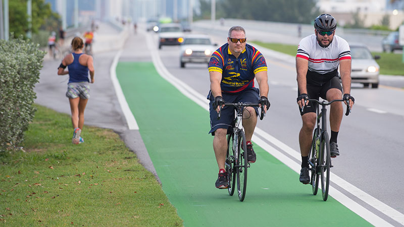 Pedestrians, cyclists, and cars on a busy street.