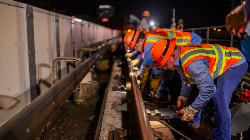 construction workers performing maintenance on Metrorail tracks at night 