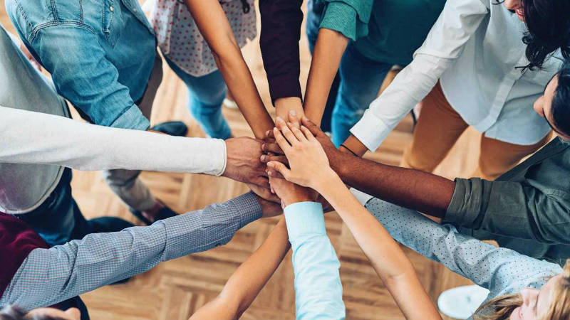 People joining hands in a huddle