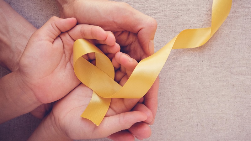 Image of hands holding a yellow ribbon.