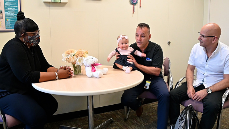 Correta Baker with her colleague and his daughter seated at a table