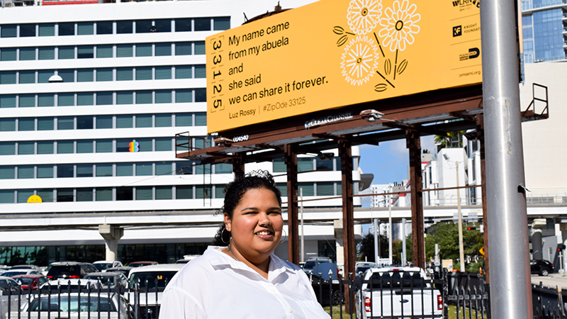 Luz Rossy and the billboard with her poem on it