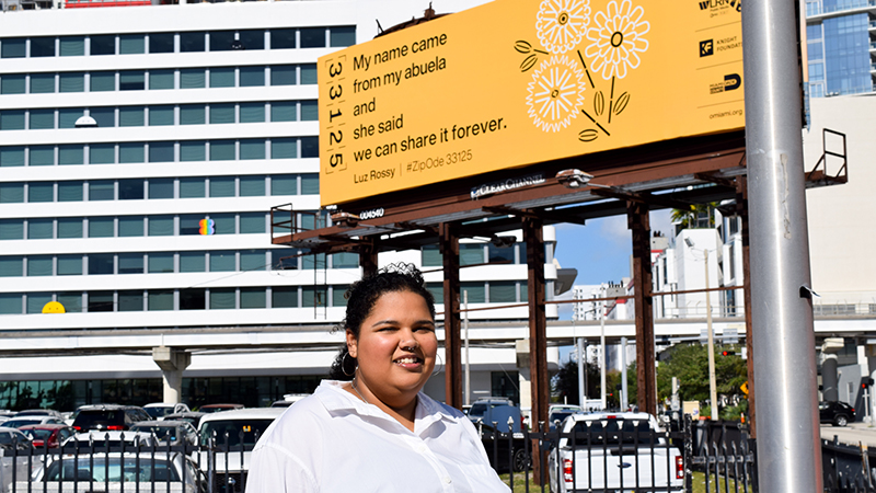 Luz Rossy and the billboard with her poem on it