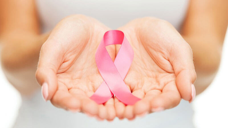 Image of hands holding pink breast cancer ribbon.