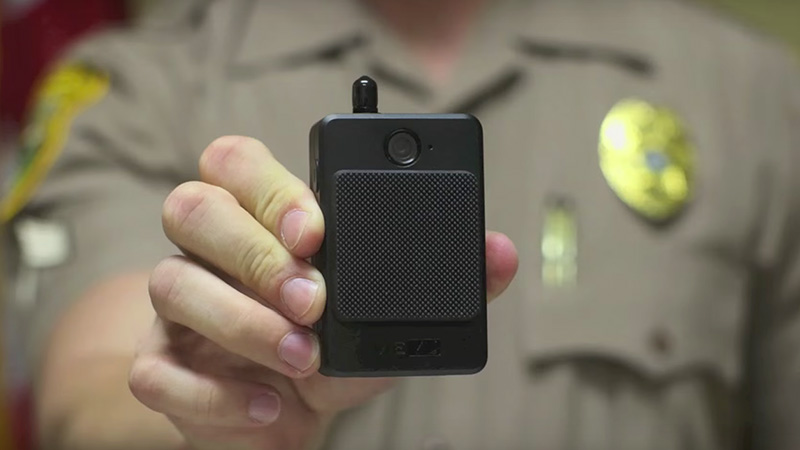 MDPD officer holding up a body camera. Links to news item.