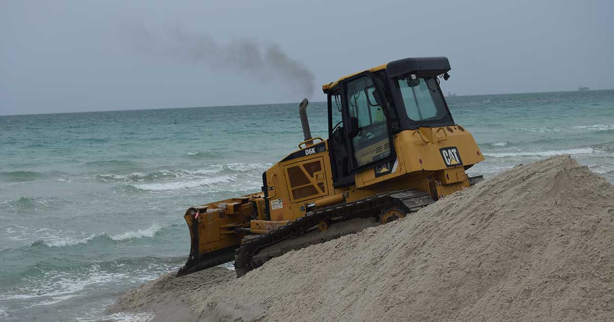 yellow tractor moving sand at the beach