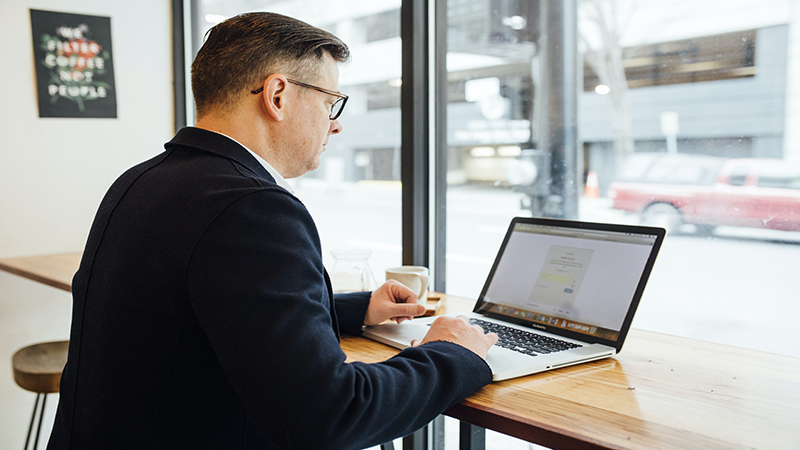 man working on computer in coffee shop