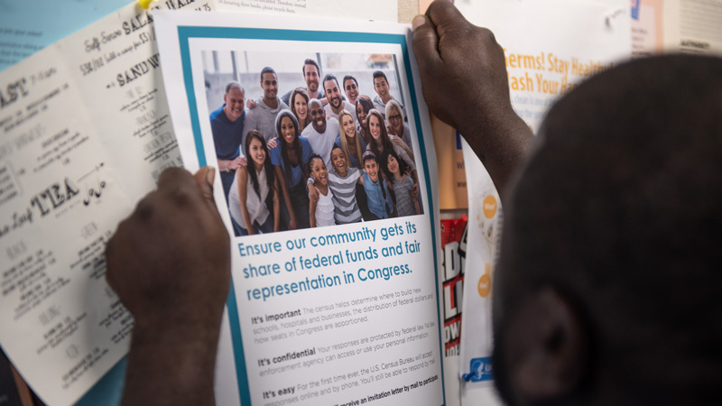 someone hanging a Census poster on a bulletin board