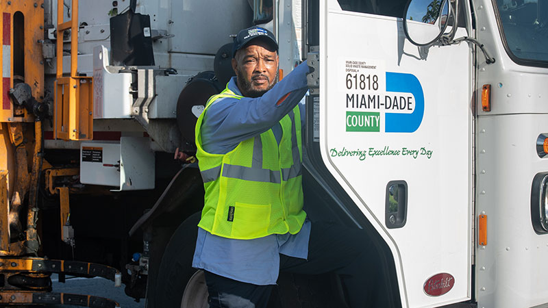 Miami-Dade Solid Waste worker standing in front of truck