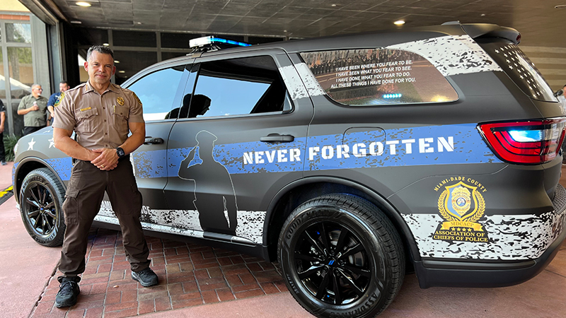 MDPD Director standing next to law enforcement appreciated vehicle