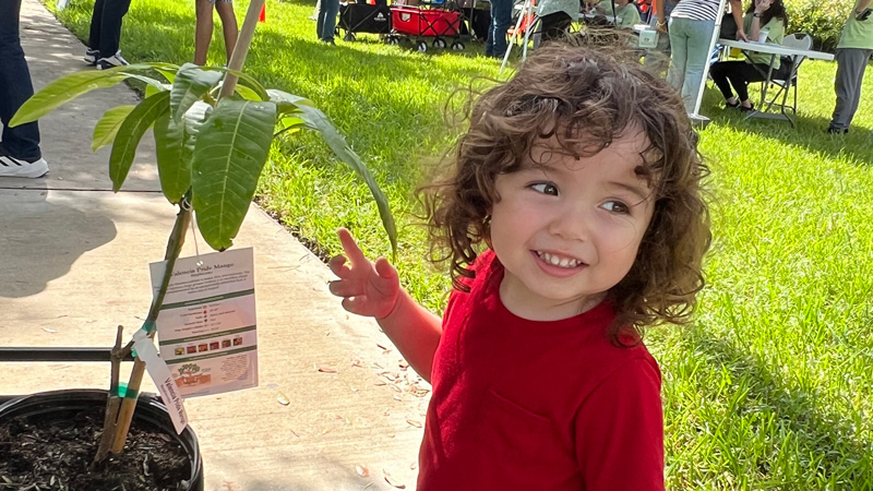 adorable child next to a potted plant