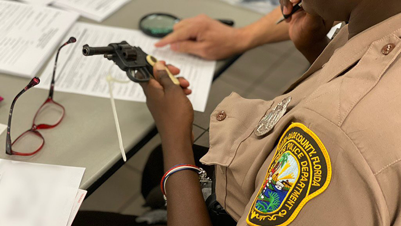 A police officer looking at the serial number of a gun