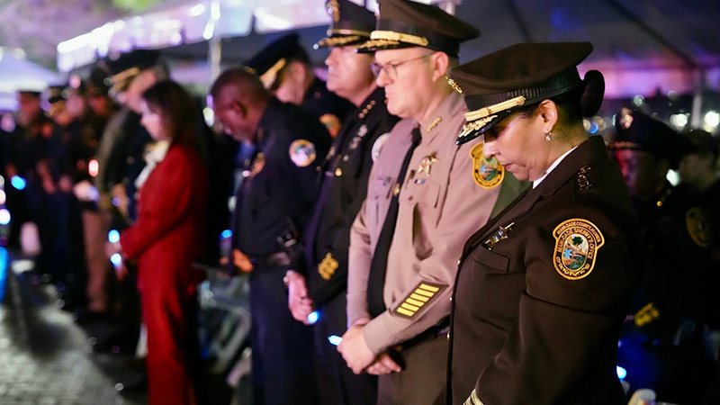 Law enforcement officers bow heads during Miami-Dade memorial ceremony.