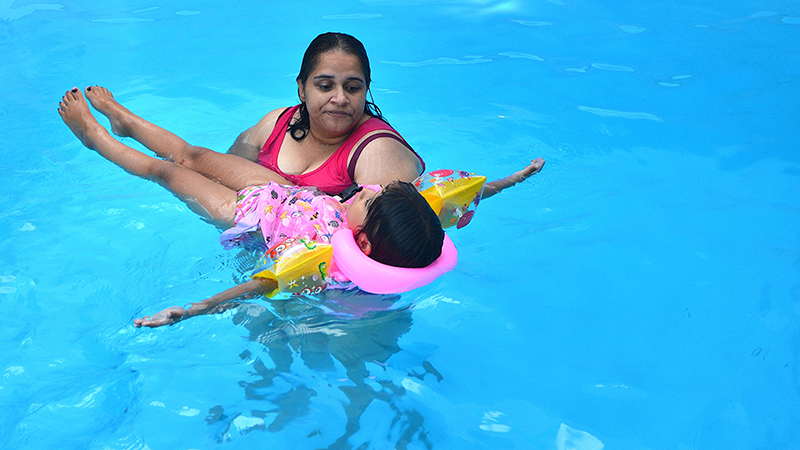 Female adult assisting girl with swimming education