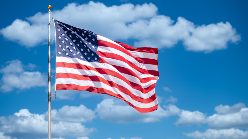 American flag attached to metal pole waving around in the sky