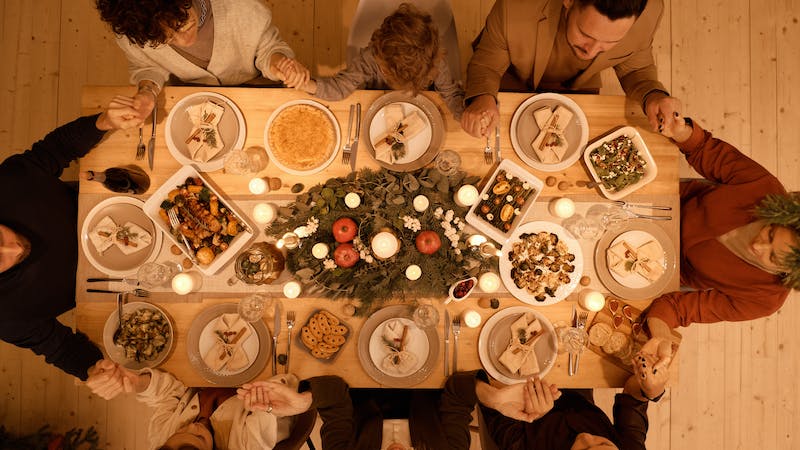family having dinner holding hands in prayer