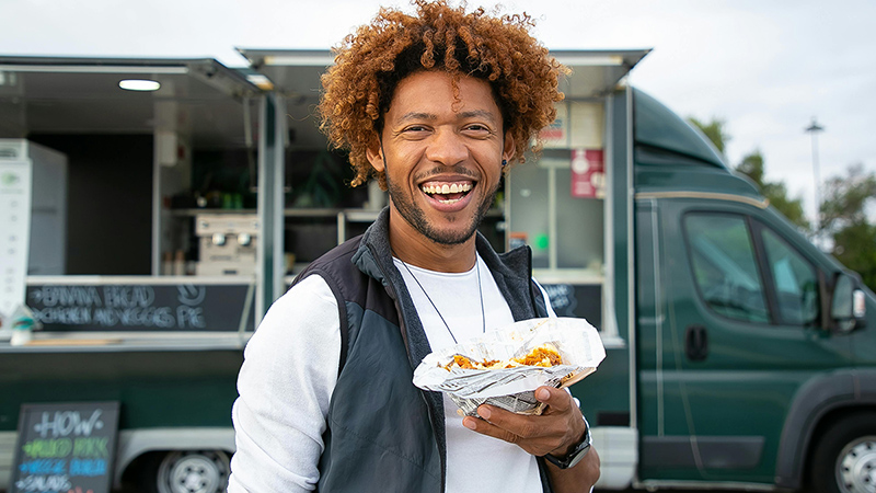 Man holding food standing in front of a food truck