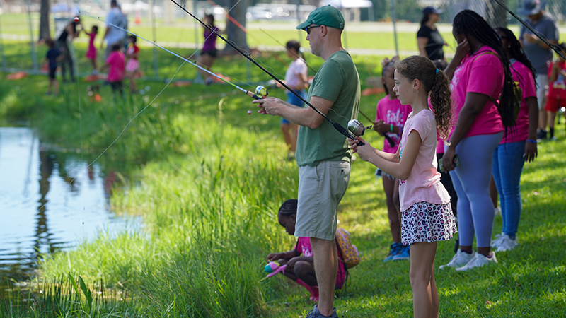 Girl, man and other people fishing at a lake