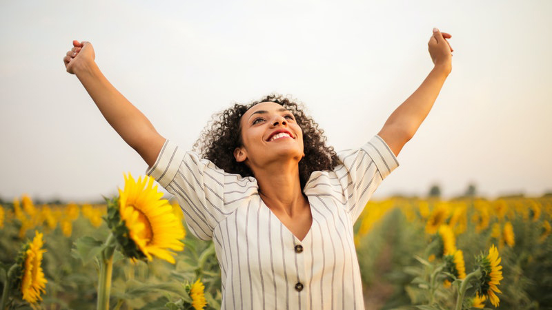 woman smiling among sunflowers