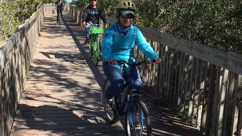 People riding bike on a boardwalk.