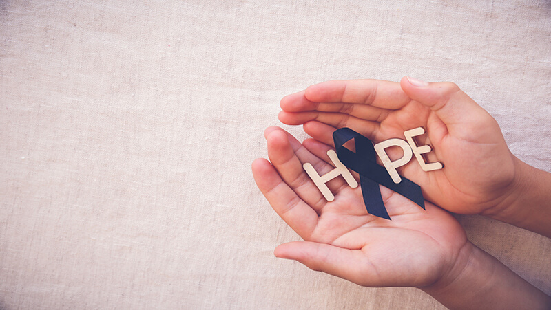 Image of hands holding letters that say hope along with a purple ribbon.