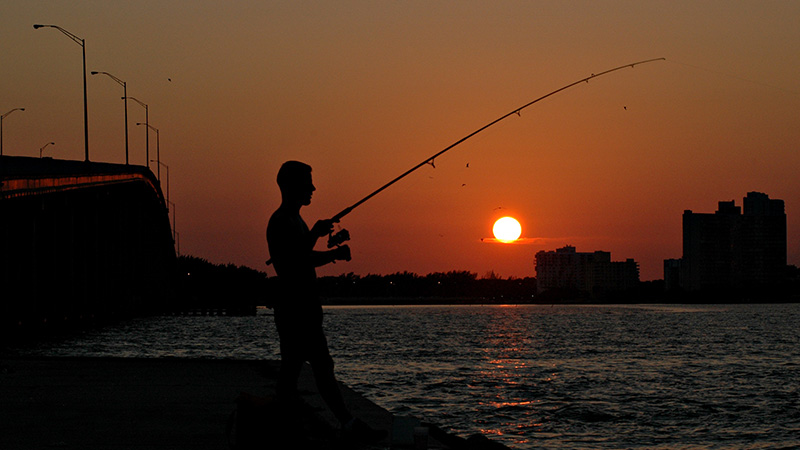 Man fishing by a bridge