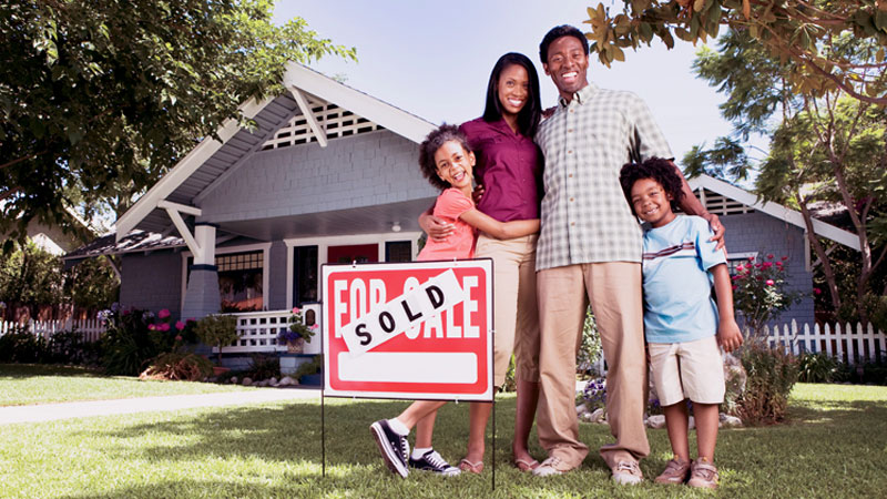 People standing and smiling in front of their new home