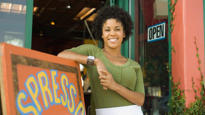 Business owner standing outside coffee shop.