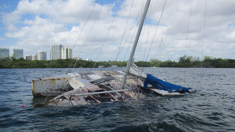 wooden trimaran, crammed with its owner’s belongings, lies abandoned in shallow water